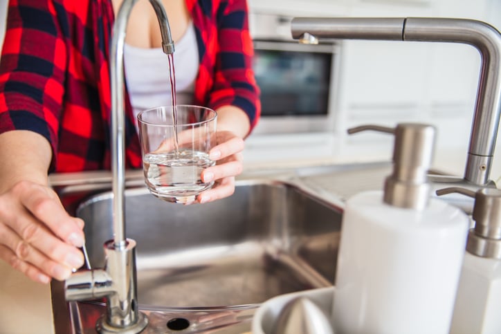 woman getting water from RO water filter faucet on sink